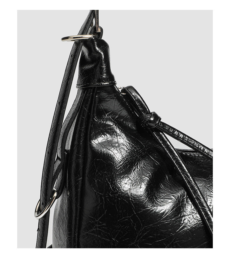 Slouchy hobo shoulder bag in glossy crinkled leather-look finish with silver-tone buckle hardware and slim adjustable strap