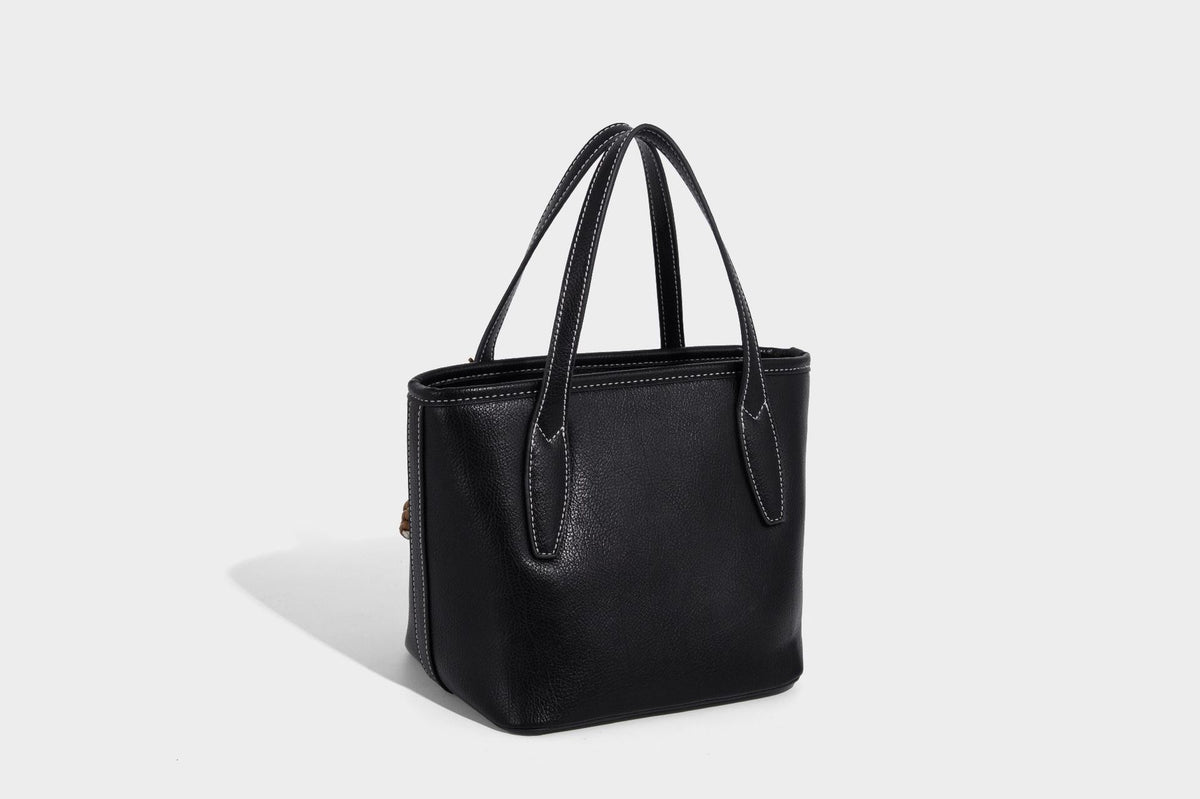 Compact structured bucket tote bag with pebbled textured finish, dual top handles, silver-tone lock hardware, and detachable