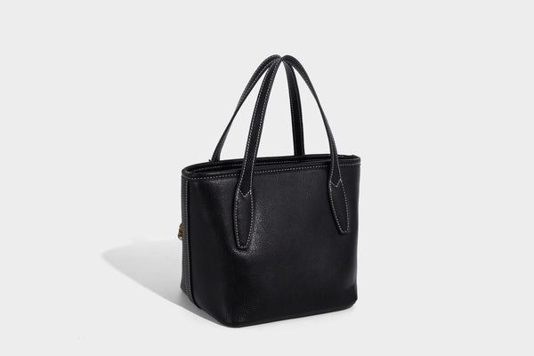 Compact structured bucket tote bag with pebbled textured finish, dual top handles, silver-tone lock hardware, and detachable