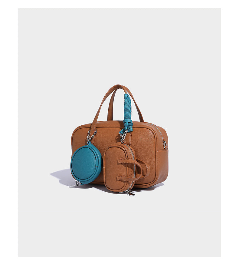 Structured pebbled leather-look Boston bowling bag in tan with blue detachable round mini pouch, dual top handles, and