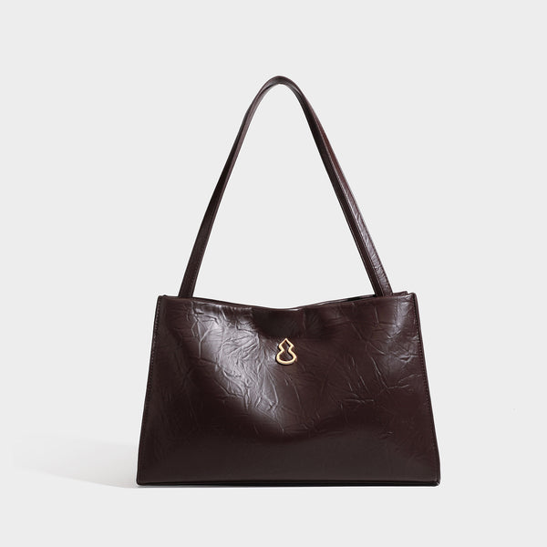 Strukturierte rechteckige Schultertasche im Tote-Stil mit glänzender, geknautschter Oberfläche in Lederoptik, langen Doppelriemen und Emblem in Goldoptik