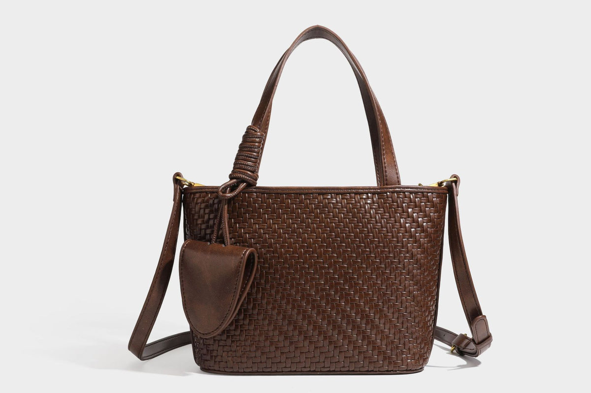 Strukturierte Tote Bag mit gewebter Oberfläche in Braun, goldfarbenen Metalldetails, seilumwickelten Tragegriffen, einer kleinen Fronttasche und weiteren Details