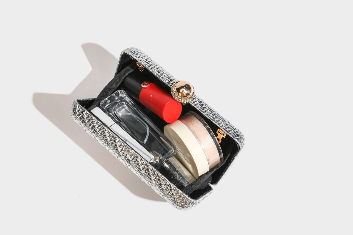 Small structured metallic woven-texture box clutch bag with jeweled kiss-lock dome clasp and slim gold chain strap, detail