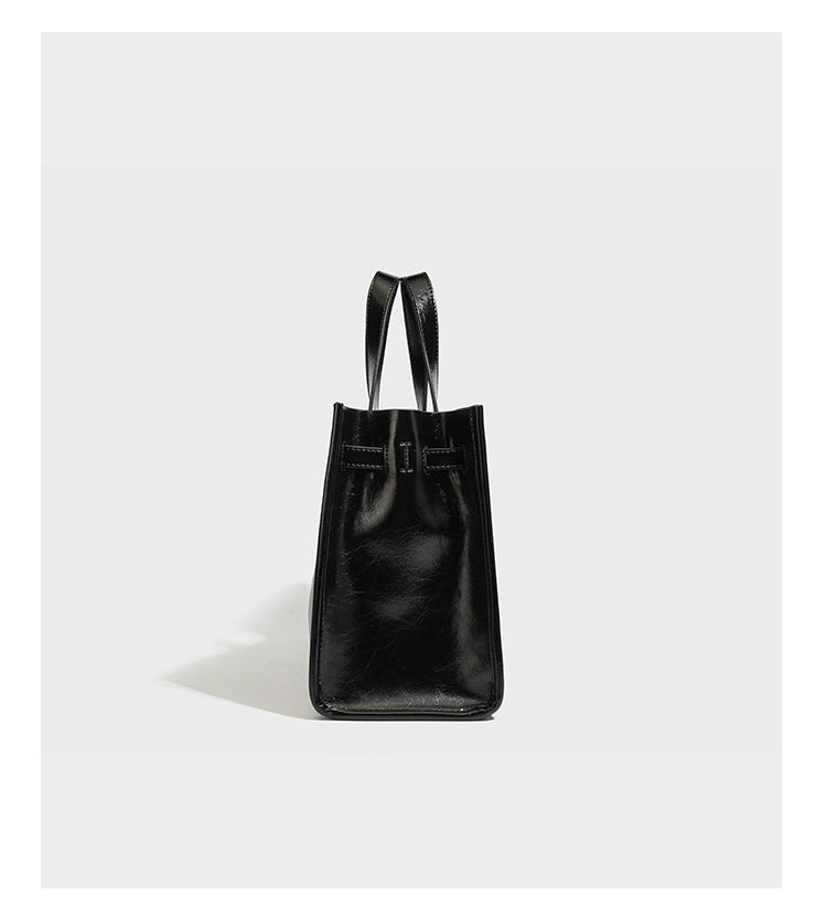 Strukturierte, glänzende Tote-Bag in Lederoptik mit silberfarbenem Drehverschluss, zwei Tragegriffen und abnehmbarem Schulterriemen, Detailansicht