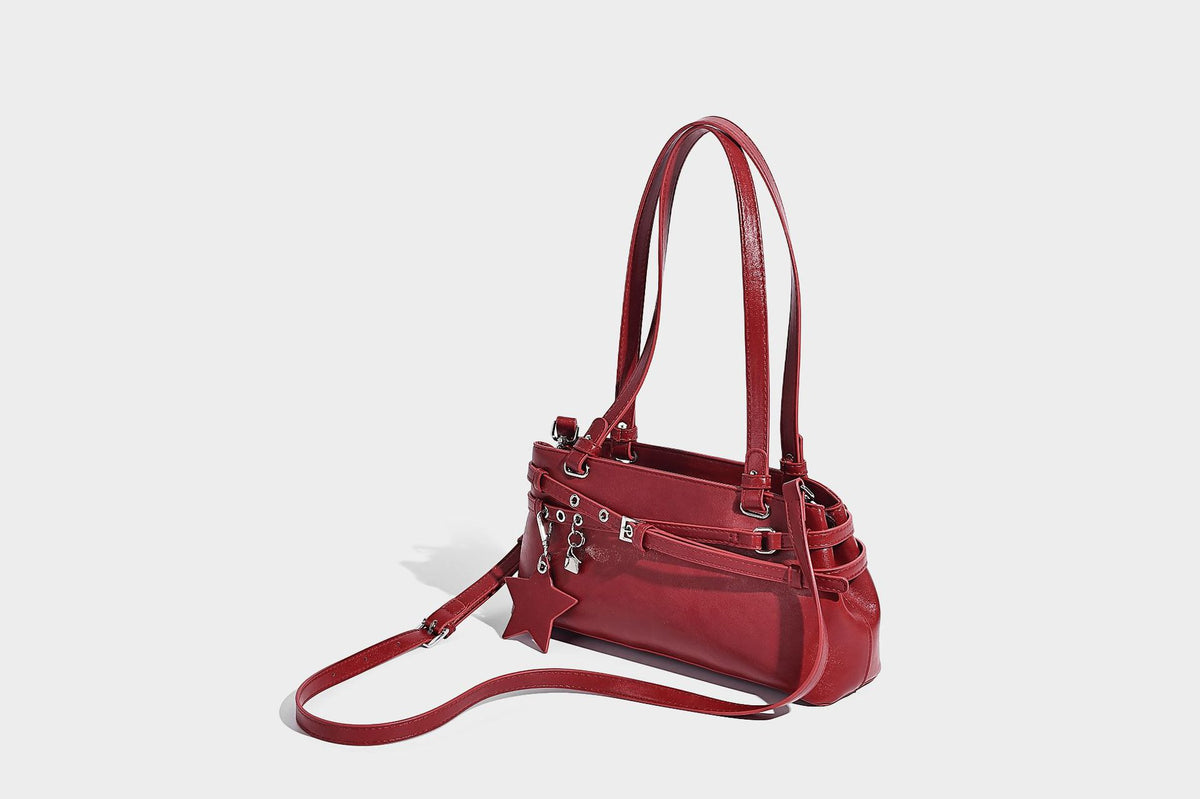 Structured glossy leather-look shoulder bag with wraparound belt straps, silver-tone hardware, and dangling star charm