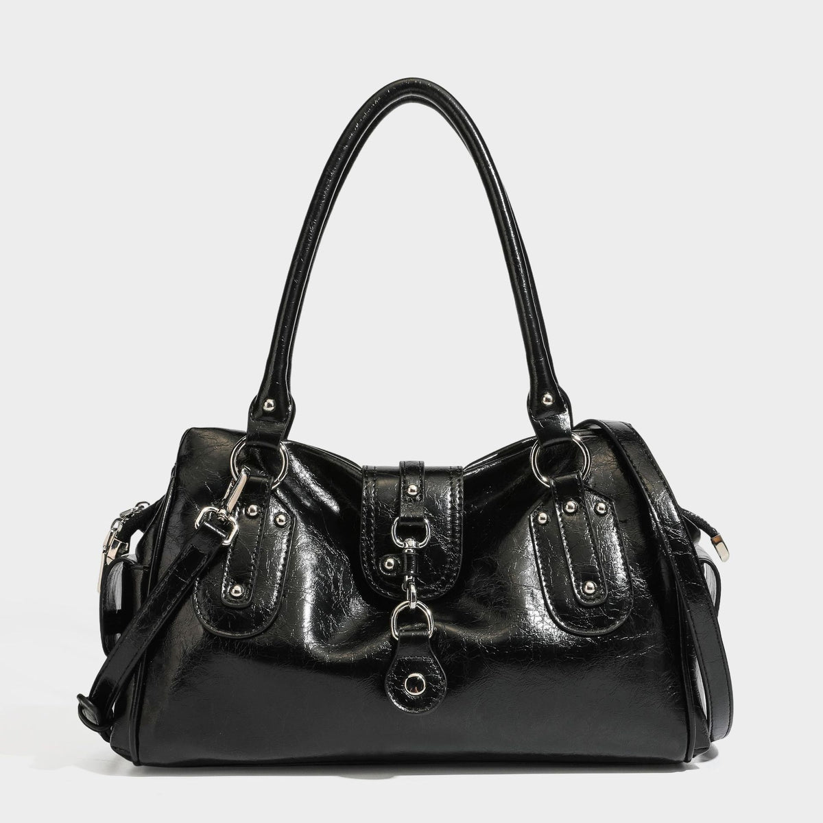 Glänzende, geknautschte Barrel-Satchel mit zwei oberen Tragegriffen, vorderem Klappen-Riemen-Panel, Ring- und Nietenbeschlägen sowie einem abnehmbaren
