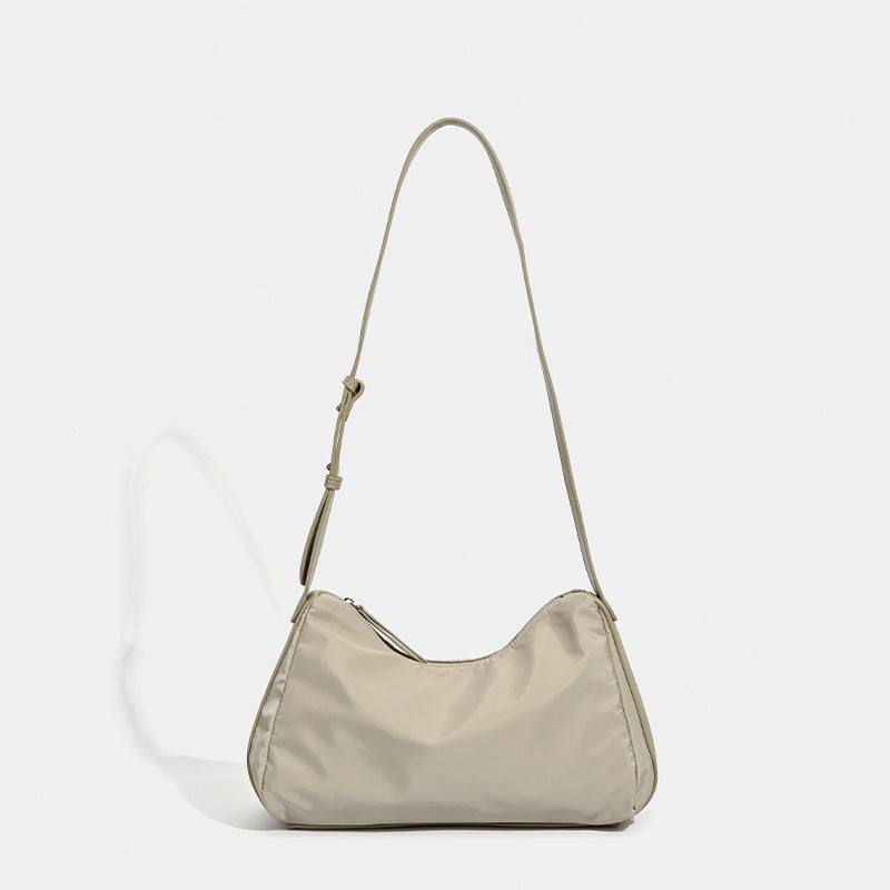 Weiche Schultertasche in Halbmondform aus glattem Nylon mit leichtem Glanz, kontrastierenden Abschlüssen in Lederoptik, schmalem verstellbarem Riemen und Reißverschluss an der Oberseite