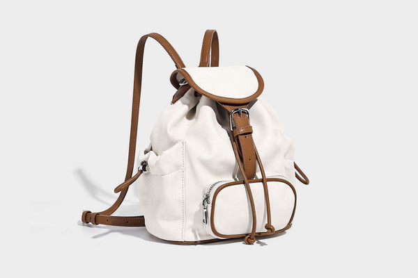 Compact denim drawstring backpack with white leather-look piping, flap-top buckle closure, front zip pocket, and silver-tone