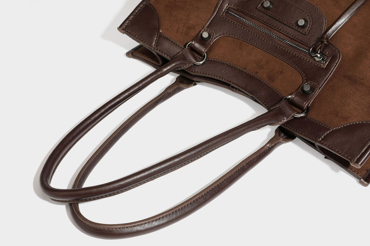 Large structured tote bag with matte suede-like body, smooth leather-look trim, front zip pocket, stud hardware, and