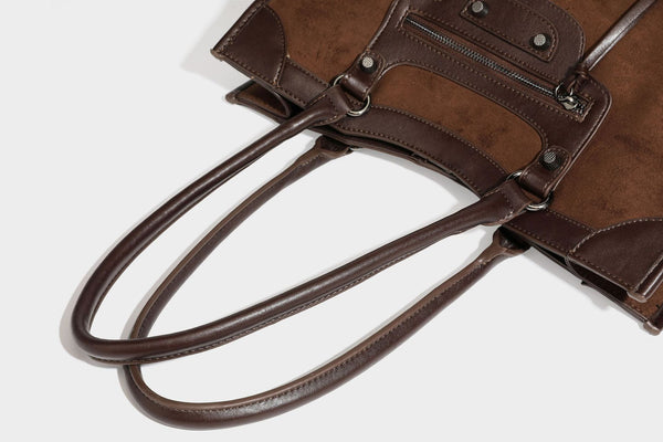 Large structured tote bag with matte suede-like body, smooth leather-look trim, front zip pocket, stud hardware, and
