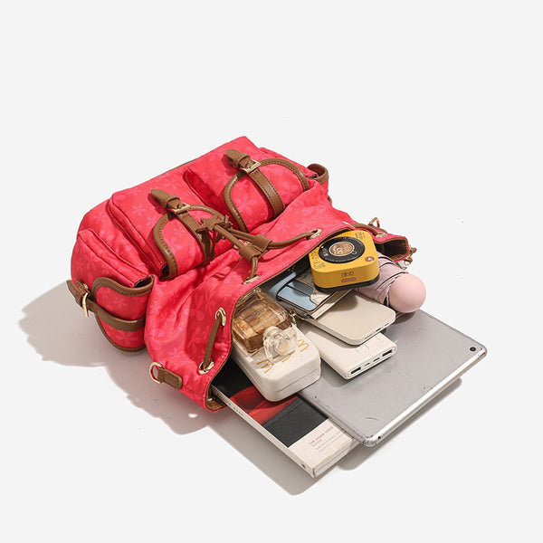 Red floral-print backpack handbag with brown leather-look trim, dual front buckle pockets, star charms, and gold-tone, detail