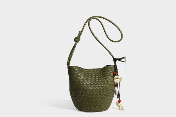 Olive green woven leather-look bucket bag with braided crossbody strap, knotted adjustment, and gold-tone tassel charm with