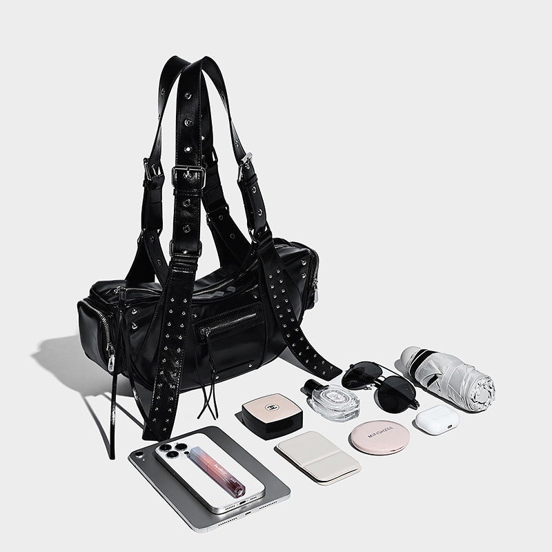 Glossy black crescent shoulder bag with silver-tone rivets, multiple zip pockets, and long adjustable studded straps, detail