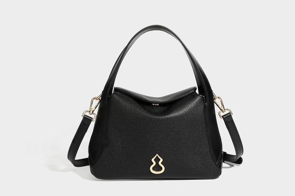 Structured pebbled leather-look shoulder bag with flap top, gold-tone emblem hardware, dual top handles, and detachable