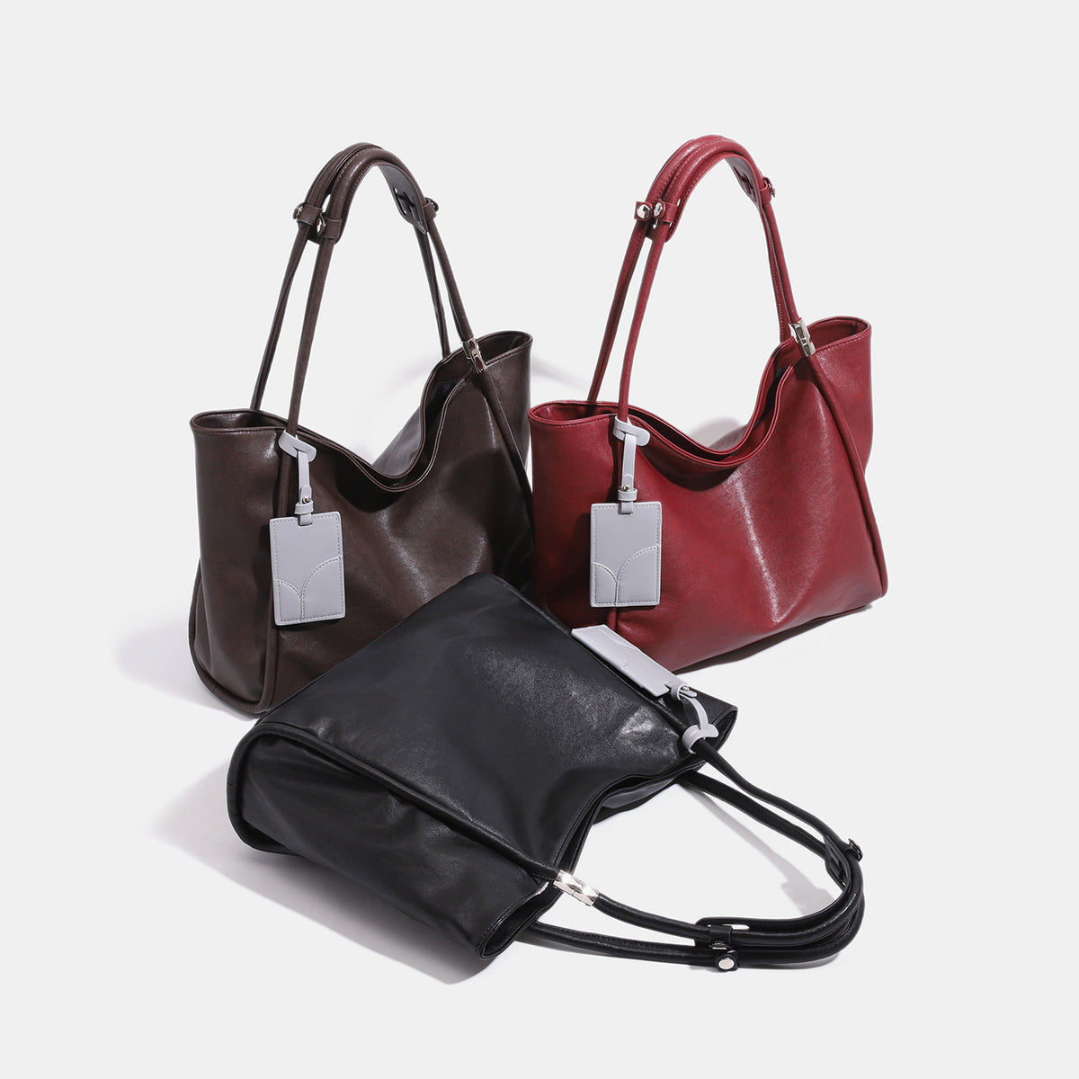 Soft slouchy leather-look tote shoulder bag with long straps, silver-tone hardware, and gray hanging tag, detail view 2