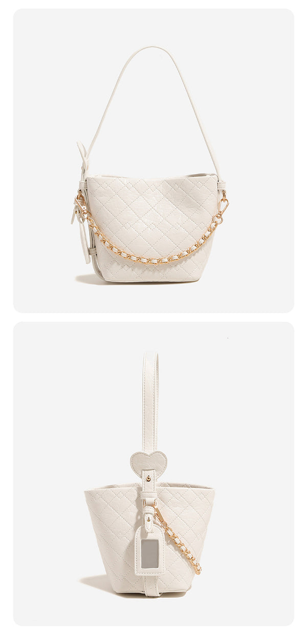 Small diamond-quilted bucket bag with gold-tone chain accent, heart strap detail, hanging tag, and matching zip coin pouch