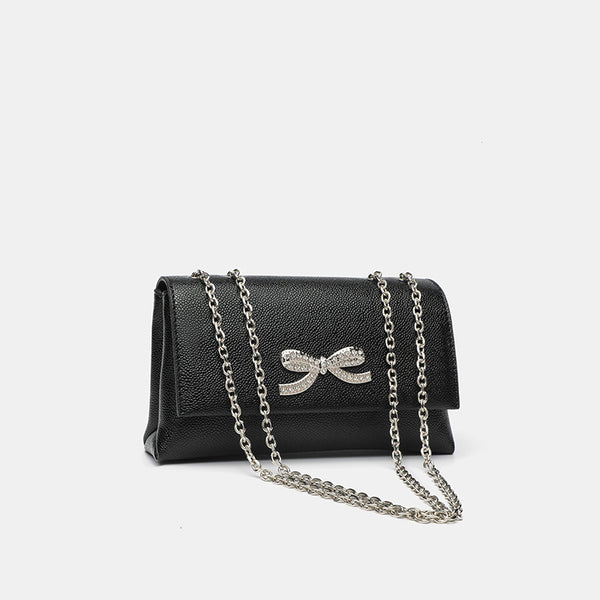 Structured rectangular flap crossbody bag with rhinestone bow and silver chain strap in pebbled finish, detail view 3