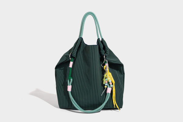 Slouchy pinstripe tote bag with braided rope handles, metal ring hardware, and colorful knotted rope charm, detail view 35