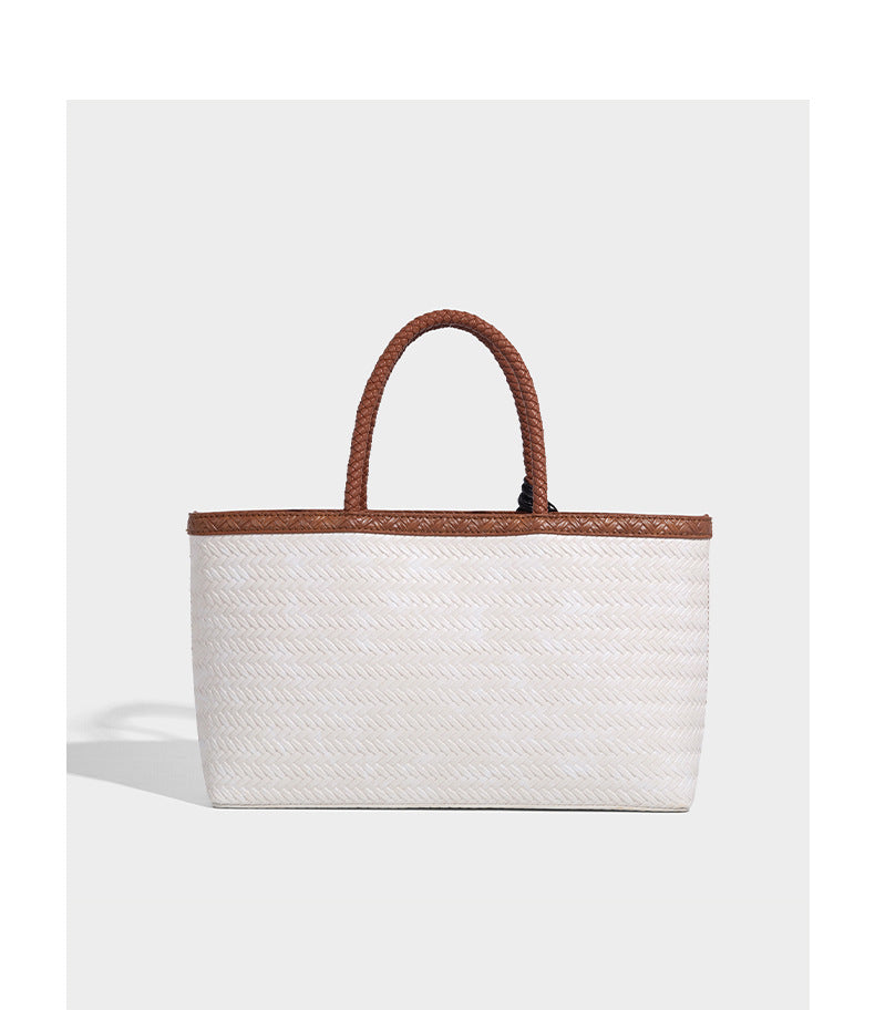 Structured woven-texture tote bag with brown braided top handles, decorative tassel charm, and detachable shoulder strap