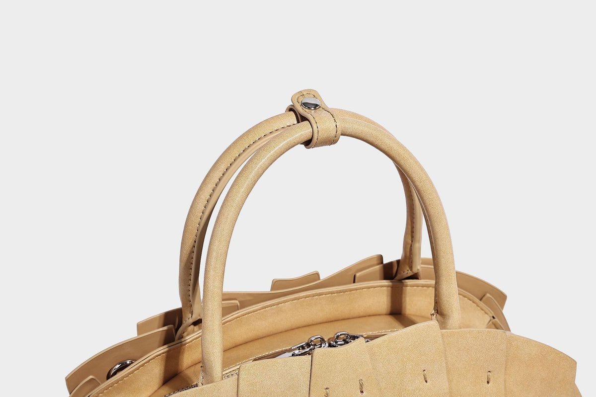 Structured dome satchel with fan-pleated leather-look exterior, dual top handles, and detachable shoulder strap, detail view