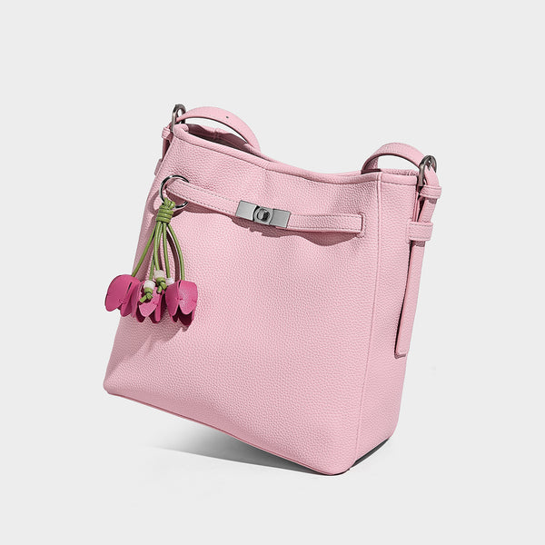 Soft-structured pebbled bucket shoulder bag with front turn-lock strap detail, adjustable strap, and hanging floral tassel