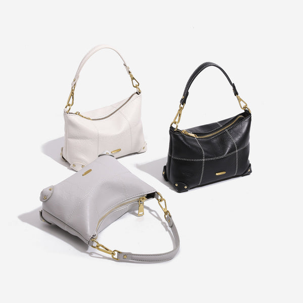 Small soft-structured shoulder bag with curved zip closure, stitched panel detailing, and gold-tone hardware, detail view 2