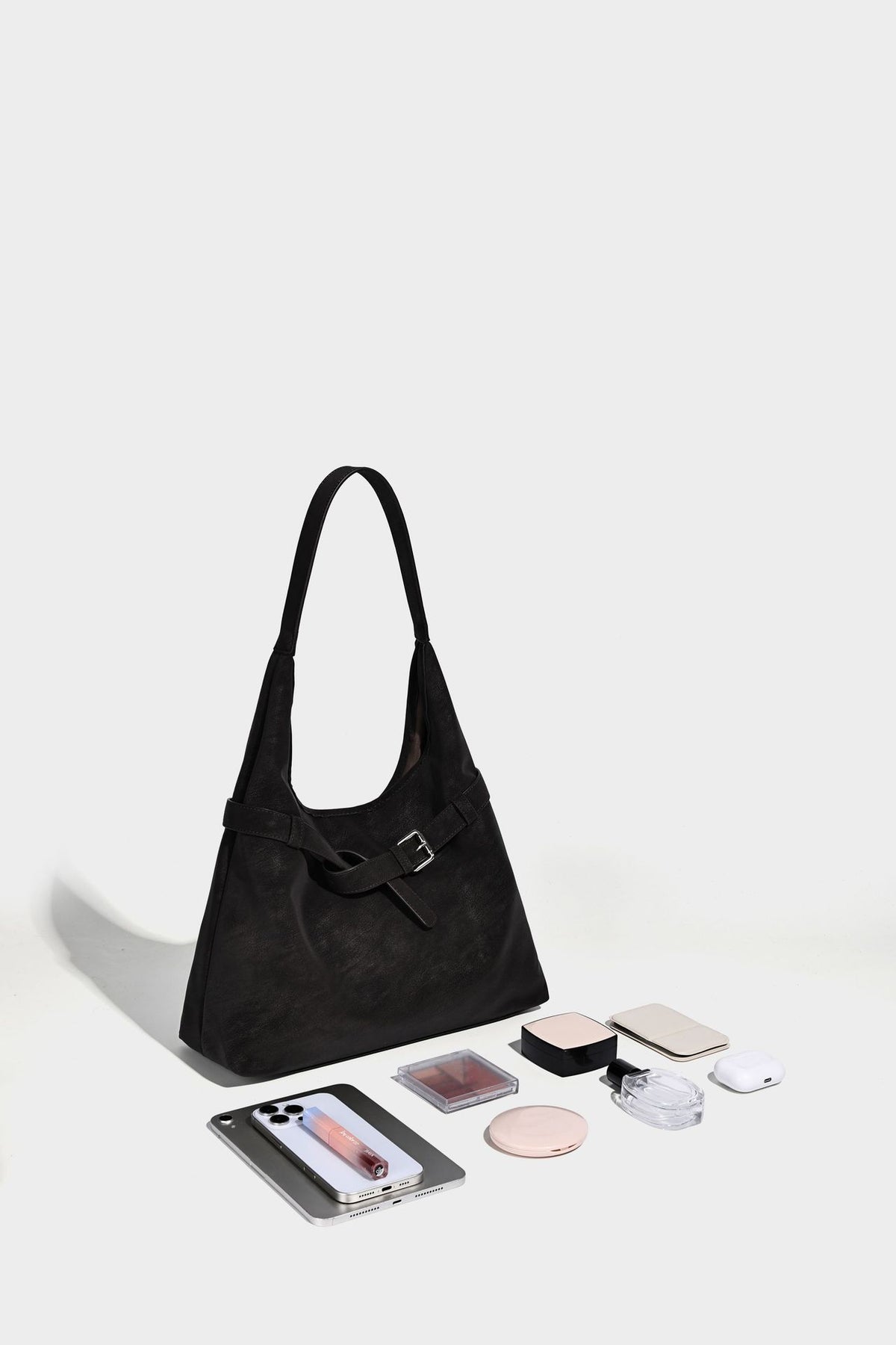 Slouchy oversized shoulder tote bag with matte textured finish, wrap-around buckle strap, and detachable front zip pouch