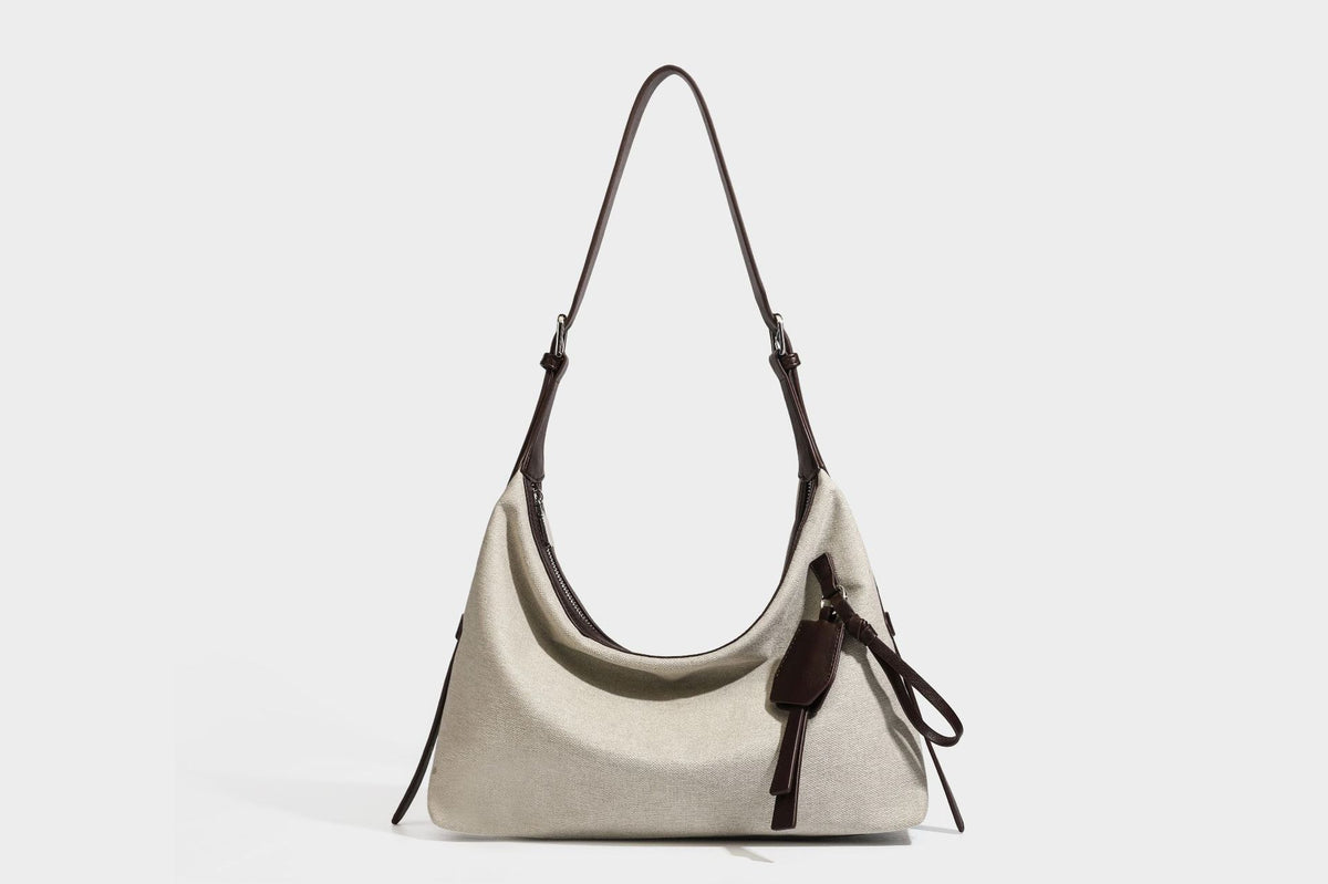 Lässig geschnittene Hobo-Schultertasche aus Canvas in Haferflockenfarbe mit dunkelbraunem Besatz in Lederoptik, silberfarbenem Reißverschluss und langem, verstellbarem