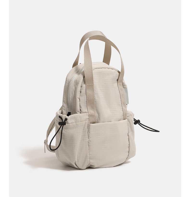 Mini rounded convertible backpack handbag in matte ripstop fabric with dual top handles, adjustable straps, and side, detail