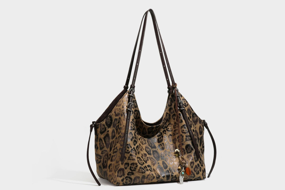 Slouchy leopard-print shoulder tote bag in tan and brown with long double straps, side tie straps, and dangling charm, detail