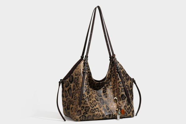 Slouchy leopard-print shoulder tote bag in tan and brown with long double straps, side tie straps, and dangling charm, detail