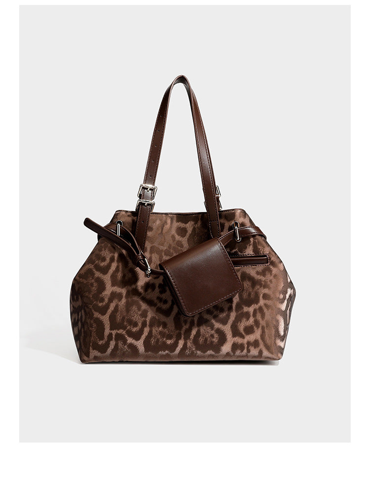 Glossy leopard-print tote bag with leather-look dark trim, dual top handles, detachable shoulder strap, and attached front