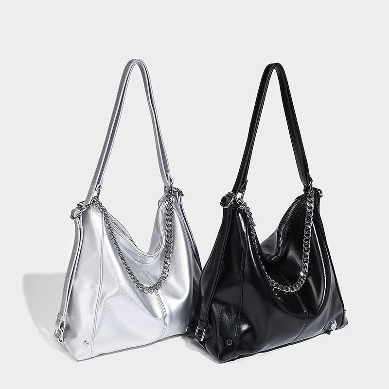 Glossy black slouchy hobo tote bag with silver-tone chain accent, top zip closure, and long shoulder straps, detail view 2