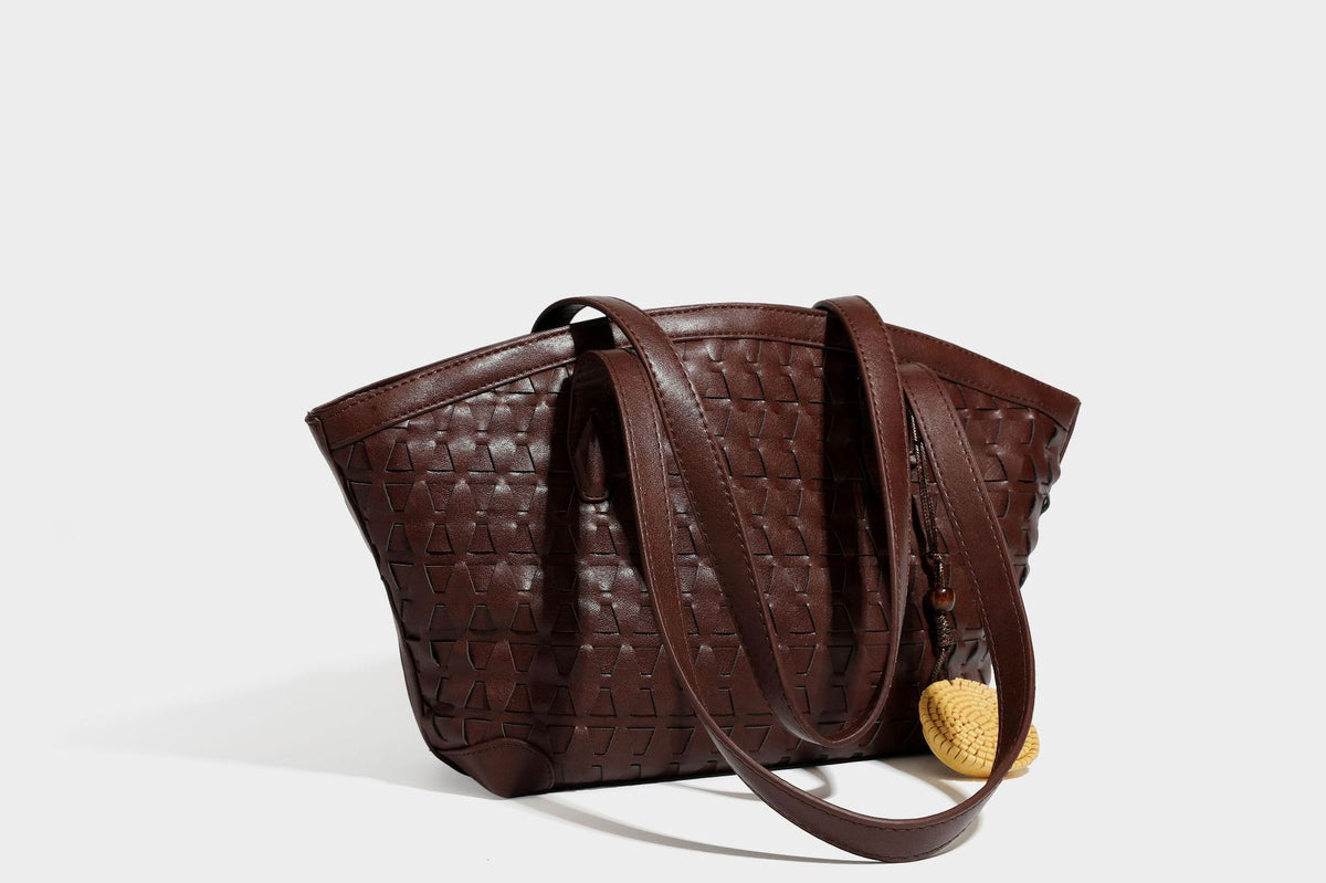 Large leather-look tote bag with geometric woven emboss, double shoulder straps, and round woven cord charm in brown, detail