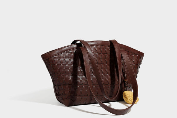 Large leather-look tote bag with geometric woven emboss, double shoulder straps, and round woven cord charm in brown, detail