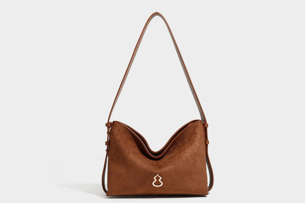 Slouchy suede-finish brown shoulder bag with long single strap and small gold-tone logo emblem on front, detail view 23