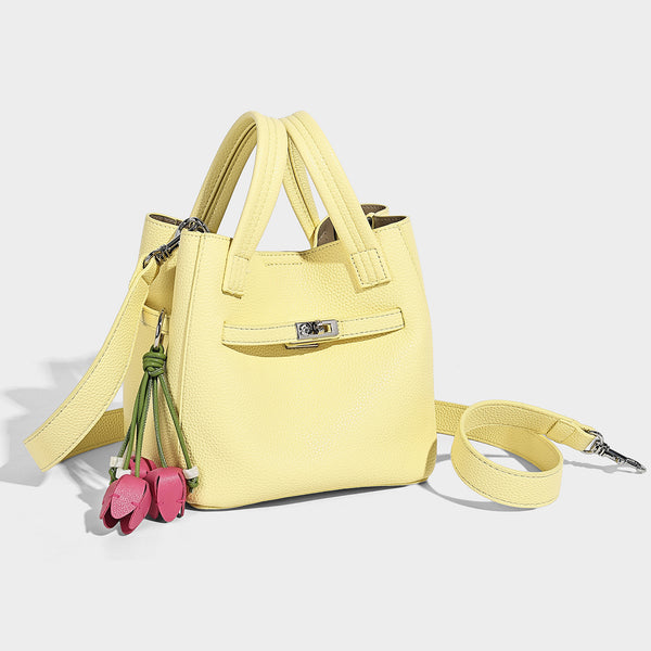 Small structured pebbled bucket tote bag with dual top handles, silver turn-lock front pocket, and detachable shoulder strap