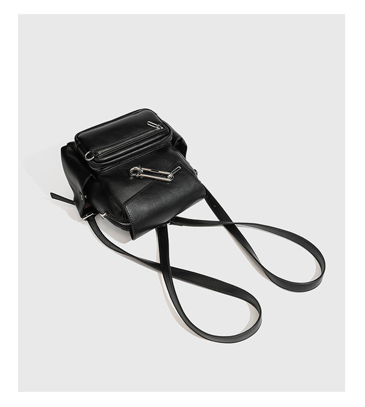 Kleiner strukturierter Rucksack in schwarzer Lederoptik mit Überschlagverschluss, silberfarbenem Metallverschluss, vorderer Reißverschlusstasche und Ring