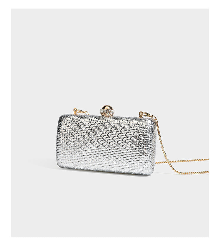 Small structured metallic woven-texture box clutch bag with jeweled kiss-lock dome clasp and slim gold chain strap, detail