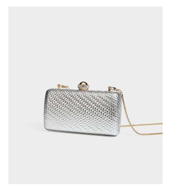Small structured metallic woven-texture box clutch bag with jeweled kiss-lock dome clasp and slim gold chain strap, detail