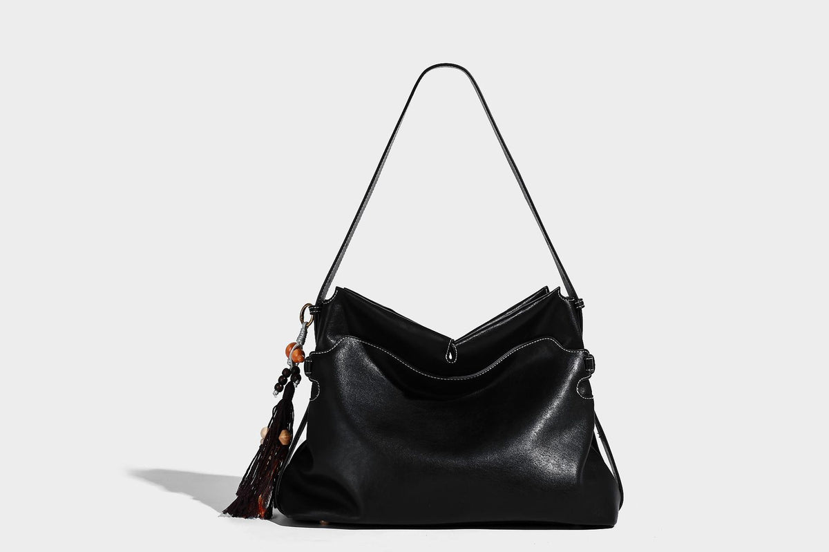 Large slouchy leather-look hobo tote bag with open top, adjustable shoulder strap, and colorful tassel bead charm, detail