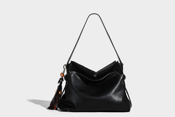 Large slouchy leather-look hobo tote bag with open top, adjustable shoulder strap, and colorful tassel bead charm, detail