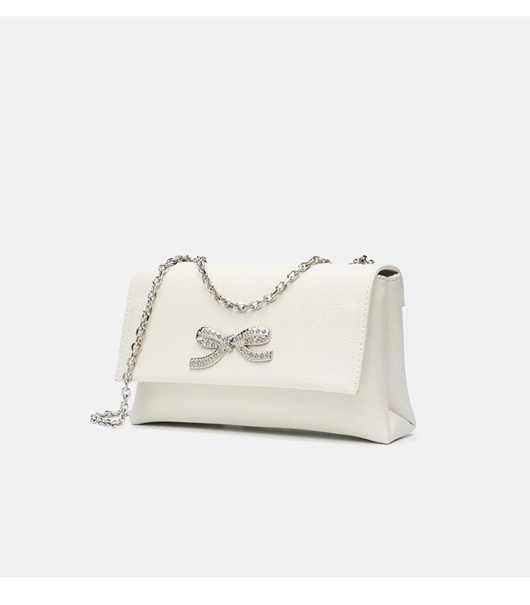Structured rectangular flap crossbody bag with rhinestone bow and silver chain strap in pebbled finish, detail view 16