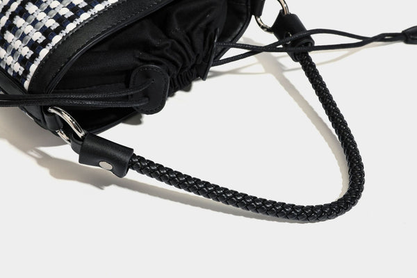 Small structured woven checker bucket bag with braided top handle, drawstring closure, and silver-tone hardware in black