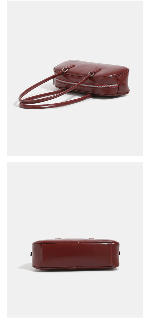 Rounded baguette shoulder bag with glossy leather-look finish, double-pull zip top, dual top handles, and silver-tone, detail