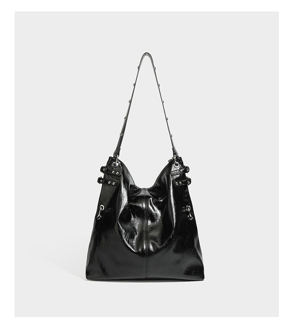 Black glossy leather-look slouchy shoulder bag with silver stud and eyelet hardware, top zip closure, front zip pocket, and