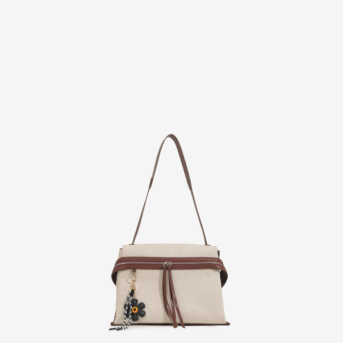 Cream canvas tote bag with brown leather-look trim, dual exterior zip pockets, long shoulder strap, and black flower charm