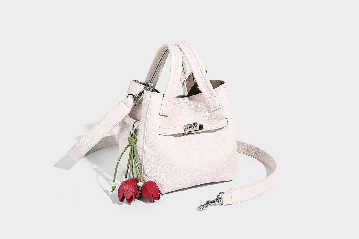 Small structured pebbled bucket tote bag with dual top handles, silver turn-lock front pocket, and detachable shoulder strap