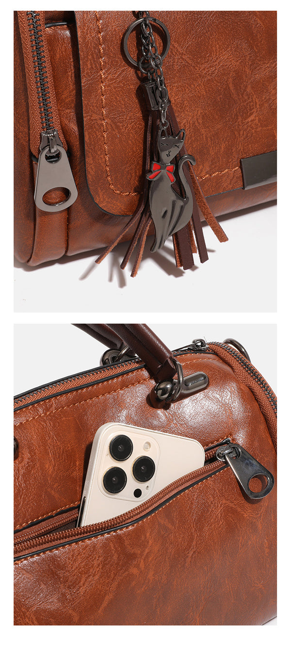 Compact structured barrel bag in distressed leather-look finish with dual top handles, detachable crossbody strap, front zip