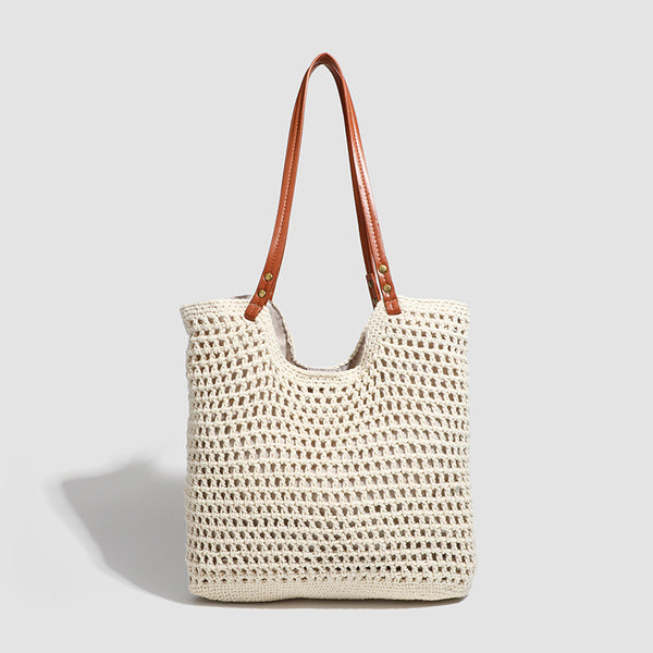 Open-knit woven tote bag with leather-look shoulder straps and brass-tone hardware in off-white, front view